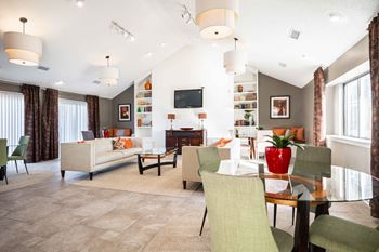 A living room with a white couch and a red vase on a glass table.